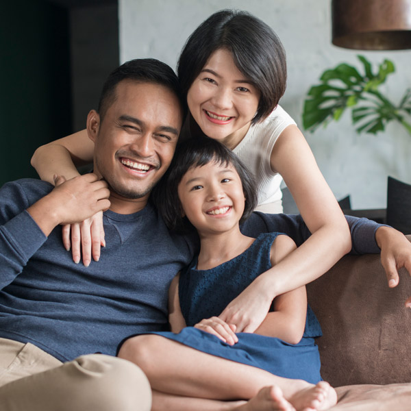 family of three smiling together in the living room